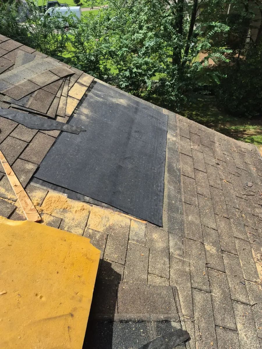 A roof leak repair in progress on a Marietta, GA home, with damaged shingles removed and fresh underlayment laid over the repaired area
