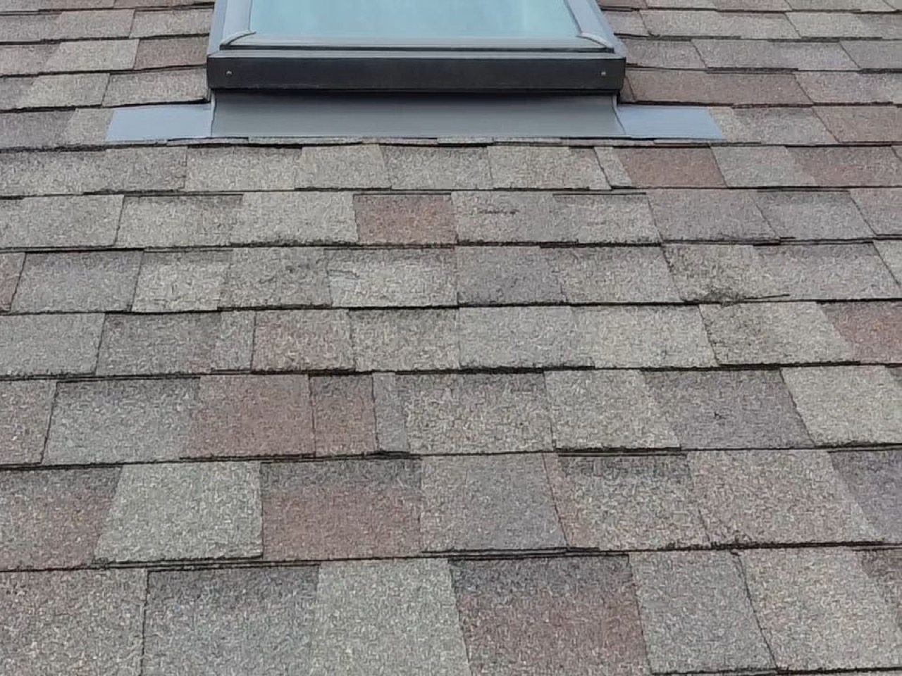 A close-up of dimensional asphalt shingles with varied tab widths around a skylight
