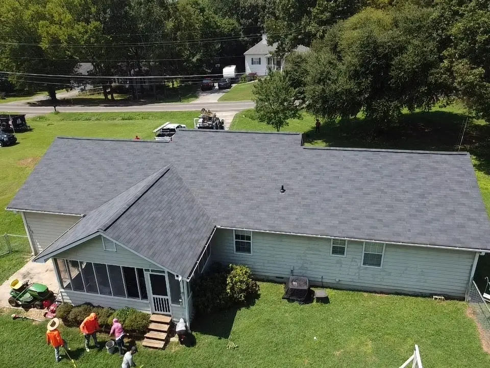 A Platinum Roofing crew cleaning up the yard of an Adairsville, GA ranch home after finishing a new gray shingle roof