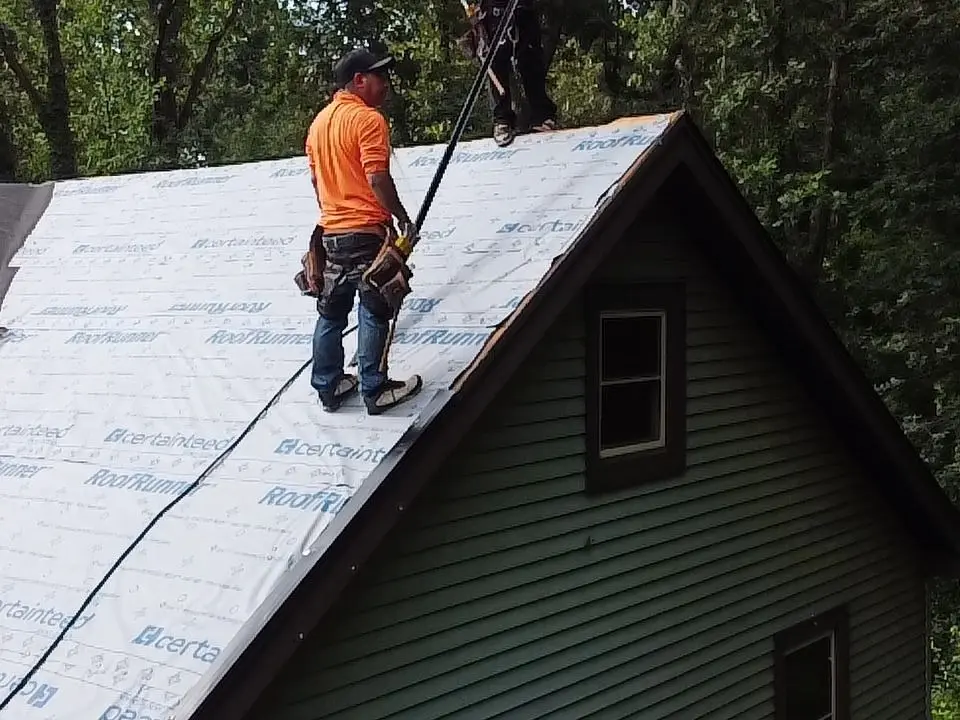 A Platinum Roofing crew member in a safety harness laying CertainTeed underlayment on a Roswell, GA home during a roof replacement