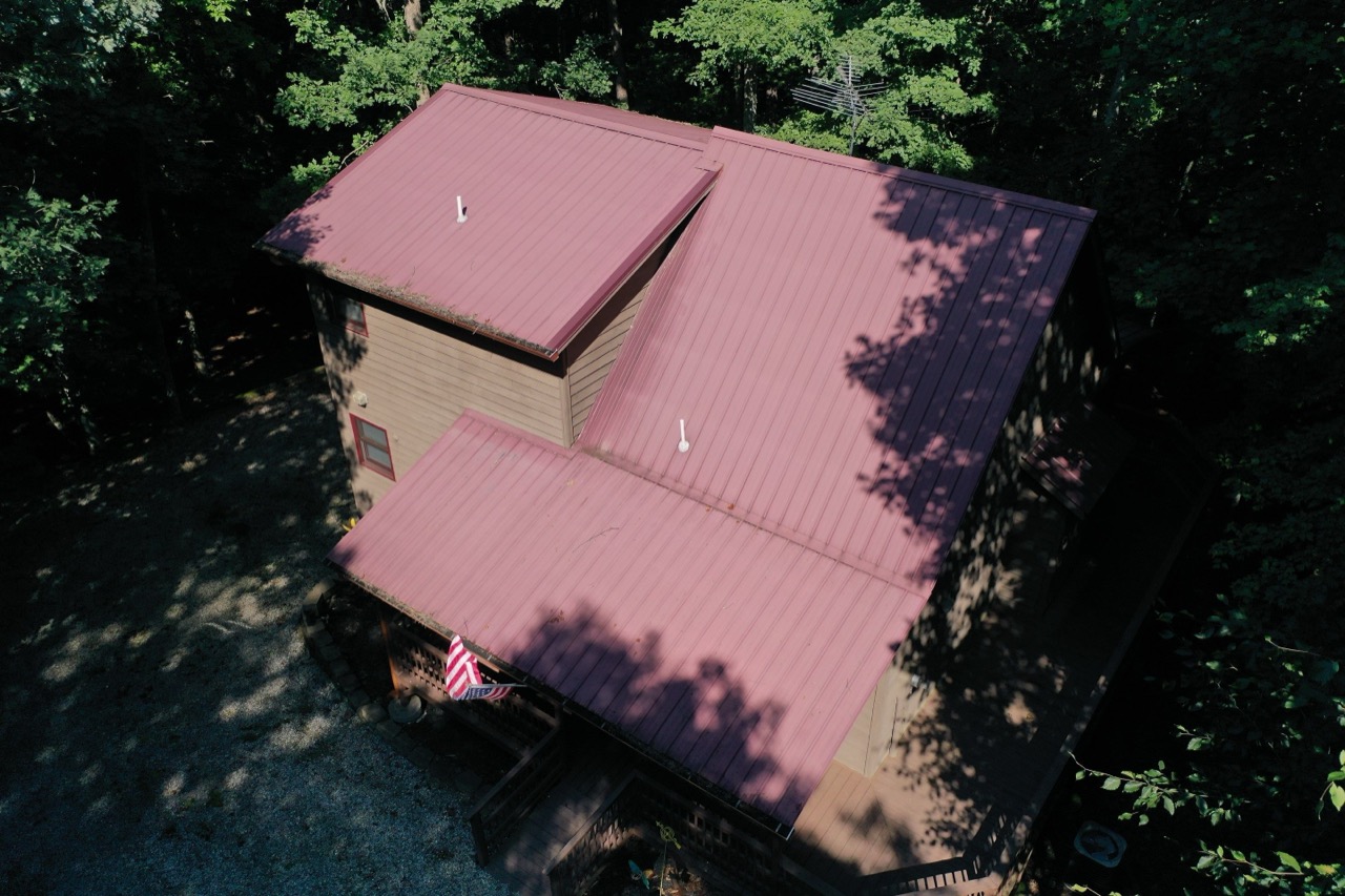 An aerial view of a red metal roof on a wooded North Georgia home