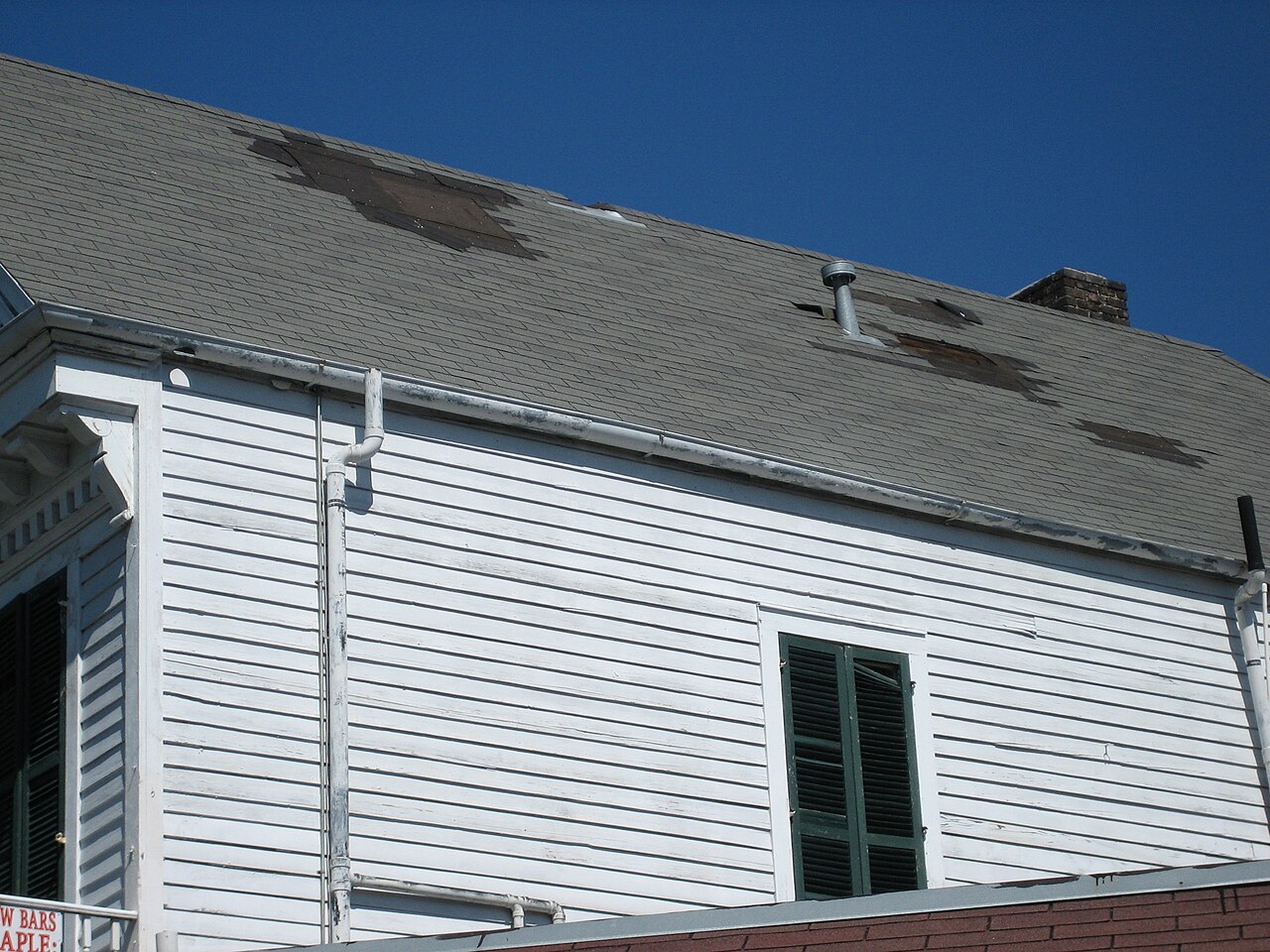 A North Georgia home with several shingles torn off by a storm, exposing the bare roof deck underneath