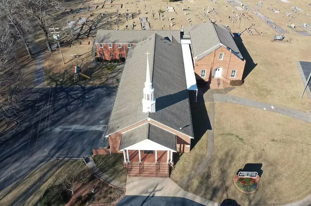 Aerial view of a large steep-slope shingle roof on a brick church, a commercial steep-slope roofing project by Platinum Roofing in North Georgia