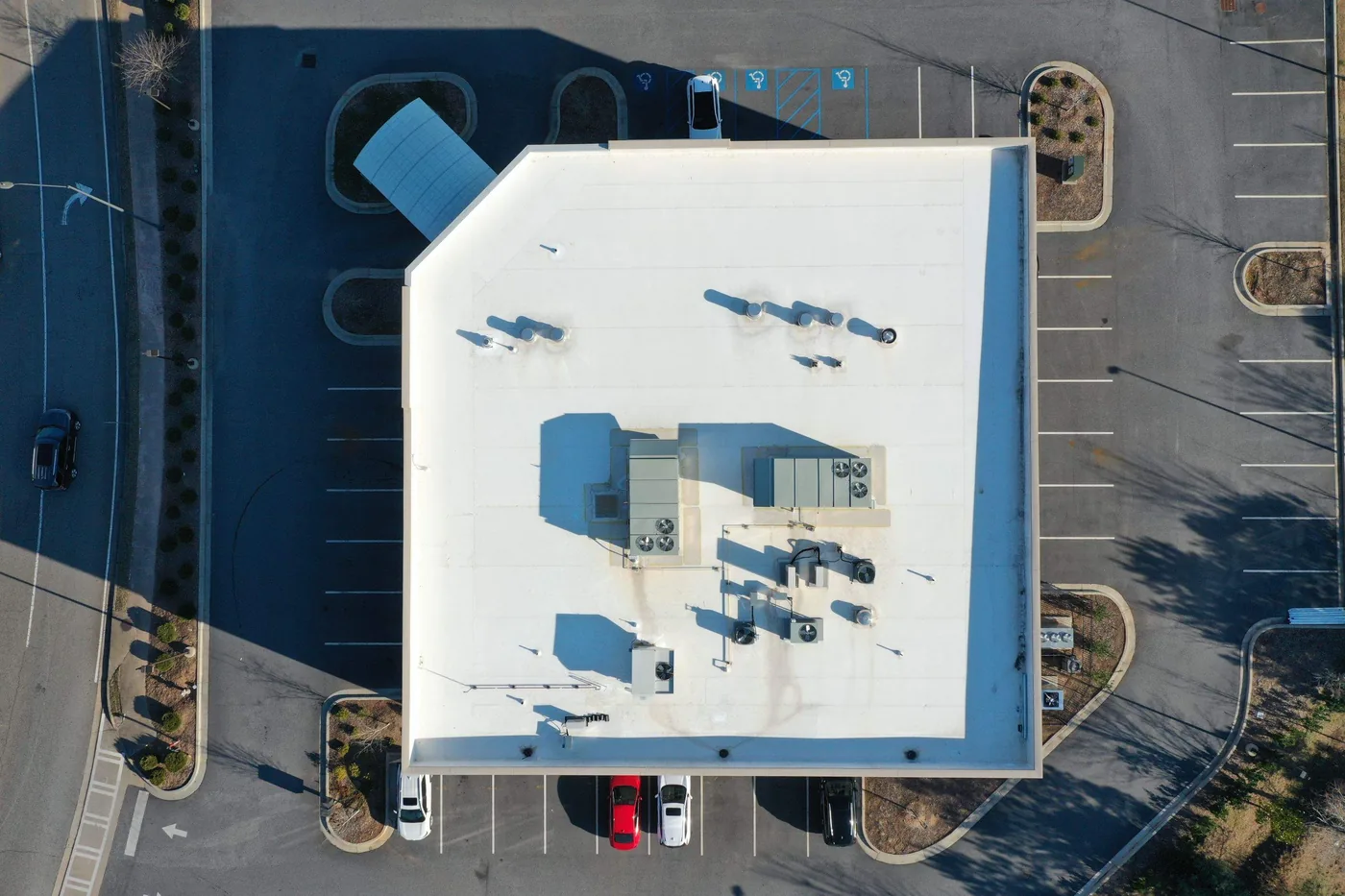 Top-down aerial of a white TPO membrane roof on an Atlanta retail building, showing welded seams and rooftop vent penetrations installed by Platinum Roofing