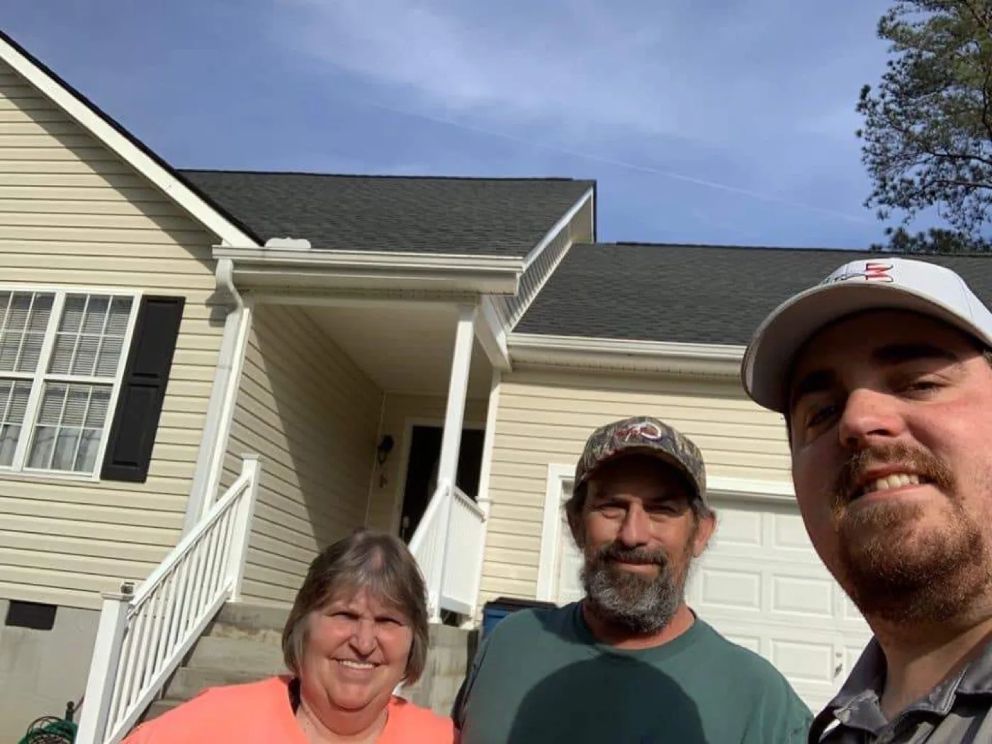 A Platinum Roofing team member with two happy homeowners in front of their completed home in North Georgia